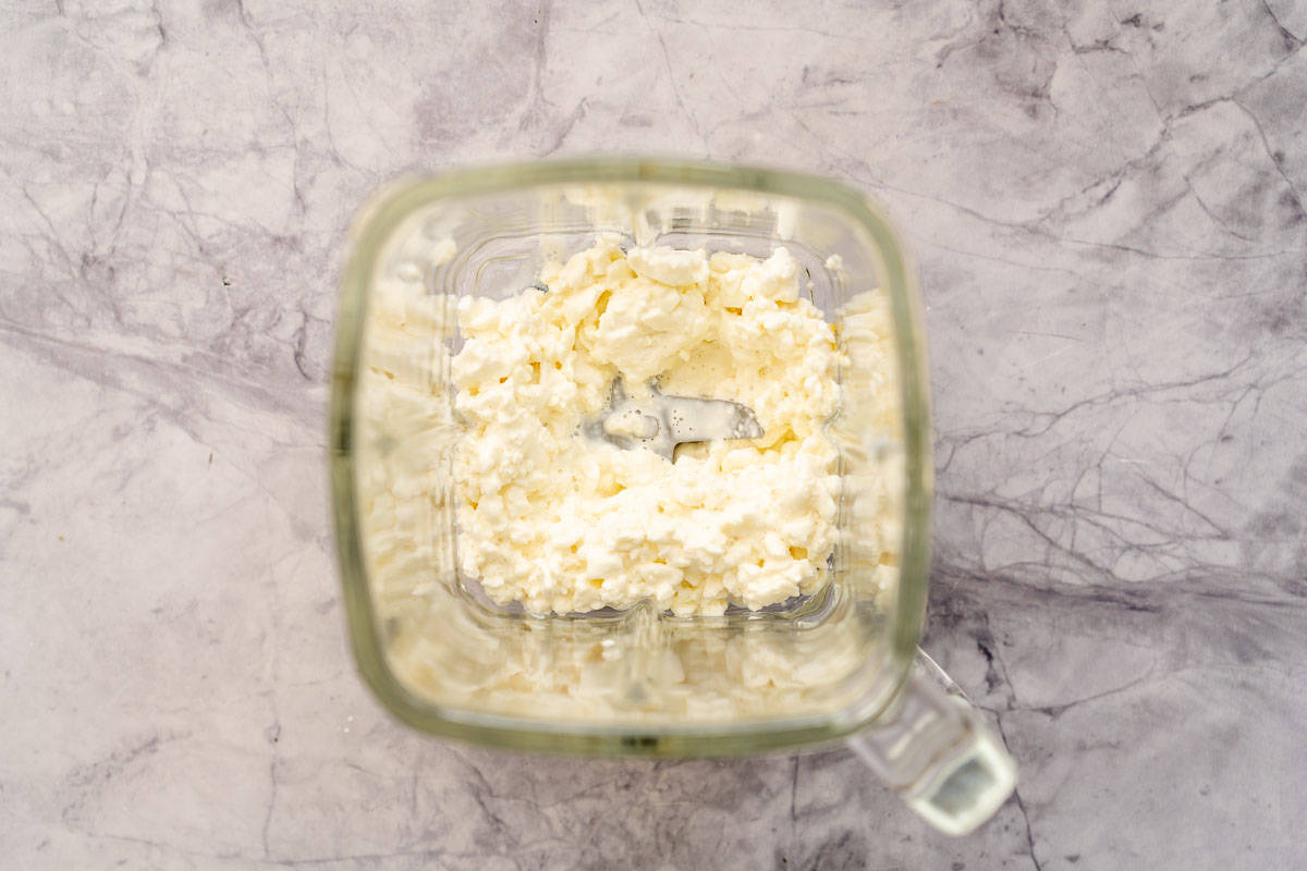 A blender full of cottage cheese sitting on the bench