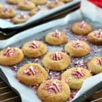 Cookies on a lined baking tray, middle filled with red and white christmas decoration.
