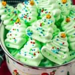 A bowl of green meringues shaped like christmas trees decorated with sprinkles.