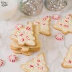 Christmas tree shaped sugar cookies decorated with icing and red Christmas decorations.
