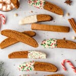 Biscotti half dipped into white chocolate and sprinkles laid out on benchtop.