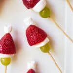 Scewers with strawberry, white marshmallow and green grape on it to look like a grinch.