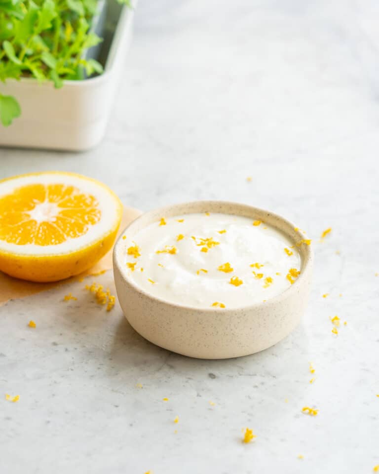 A small ramekin filled with a feta dip topped with grated lemon zest.