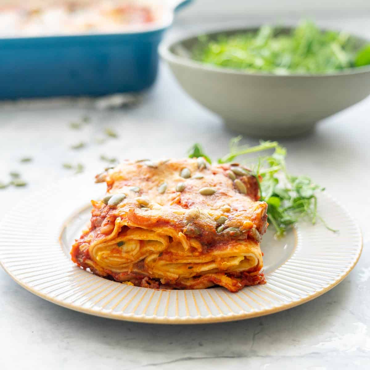 A serving of Butternut Squash Pasta and a side salad on a plate.