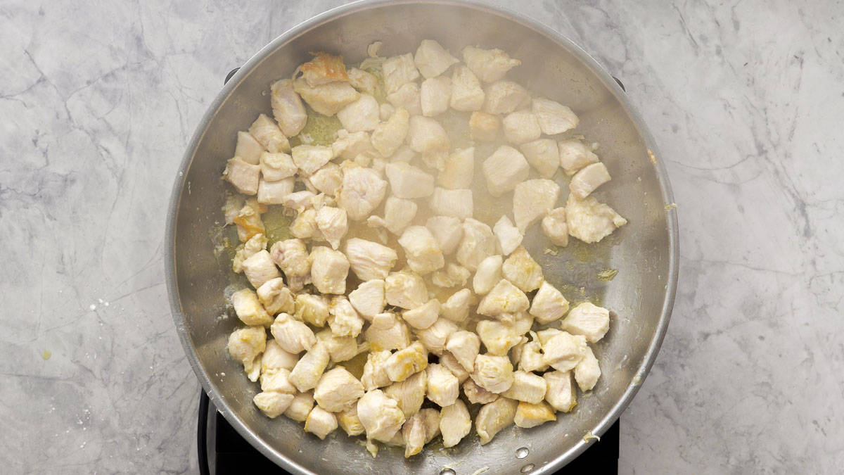 Diced chicken browning in the frying pan on a bench element