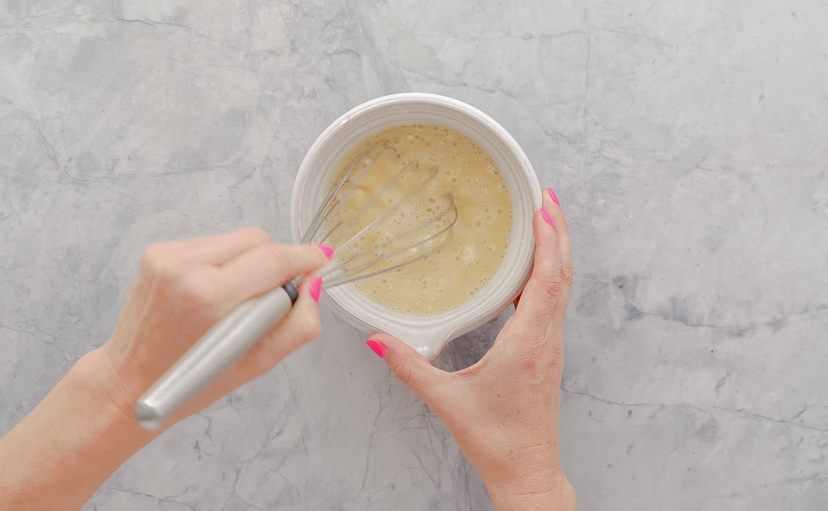 Stock and cornflour being whisked together in a small bowl.