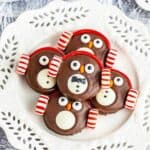 Five cookies on benchtop decorated as penguins.