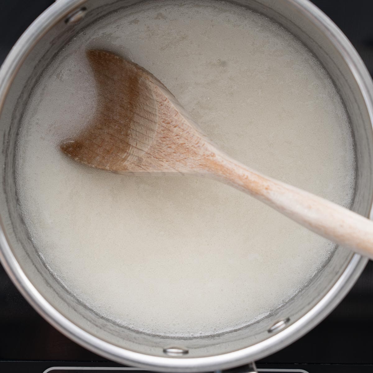 Milk and sugar heating in a saucepan over medium heat