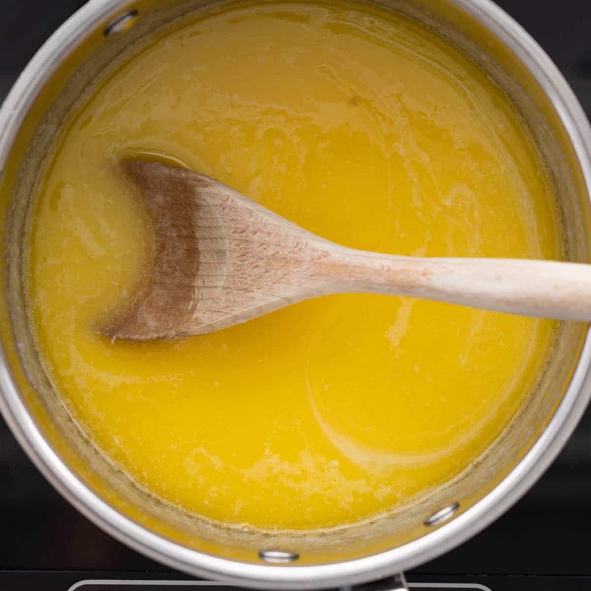 Fudge mixture brought to a boil in a saucepan on the bench element with a wooden spoon resting on the side