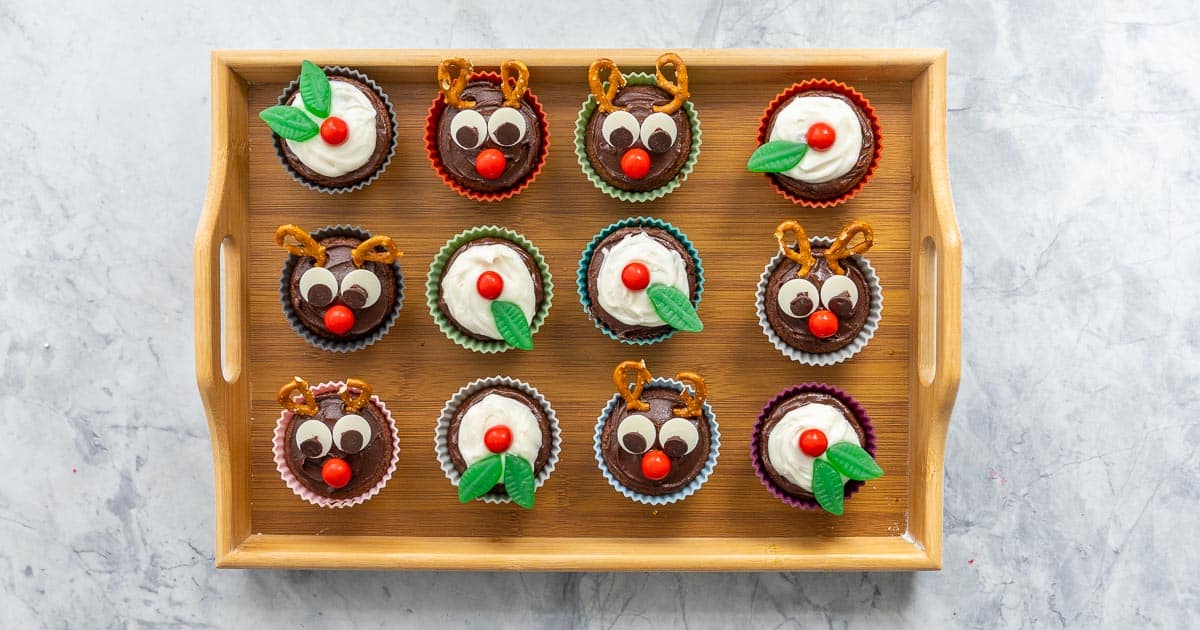 A tray of christmas cupcakes, half decorated to look like figgy puddings, half decorated to look like reindeer.