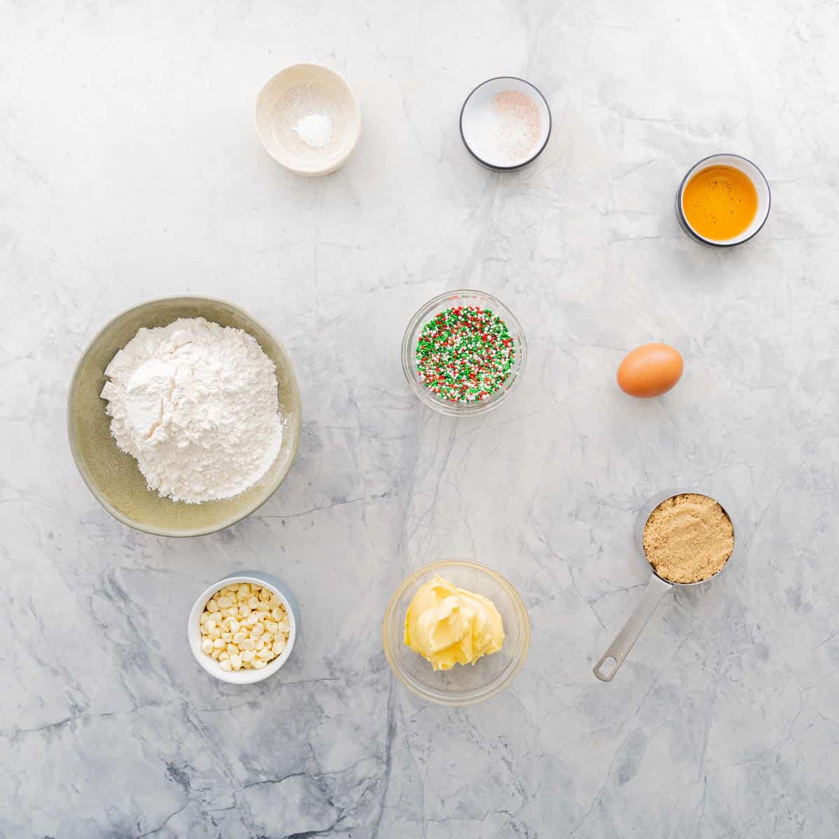 All the ingredients to make Christmas Sprinkle Cookies all laid out on the bench.