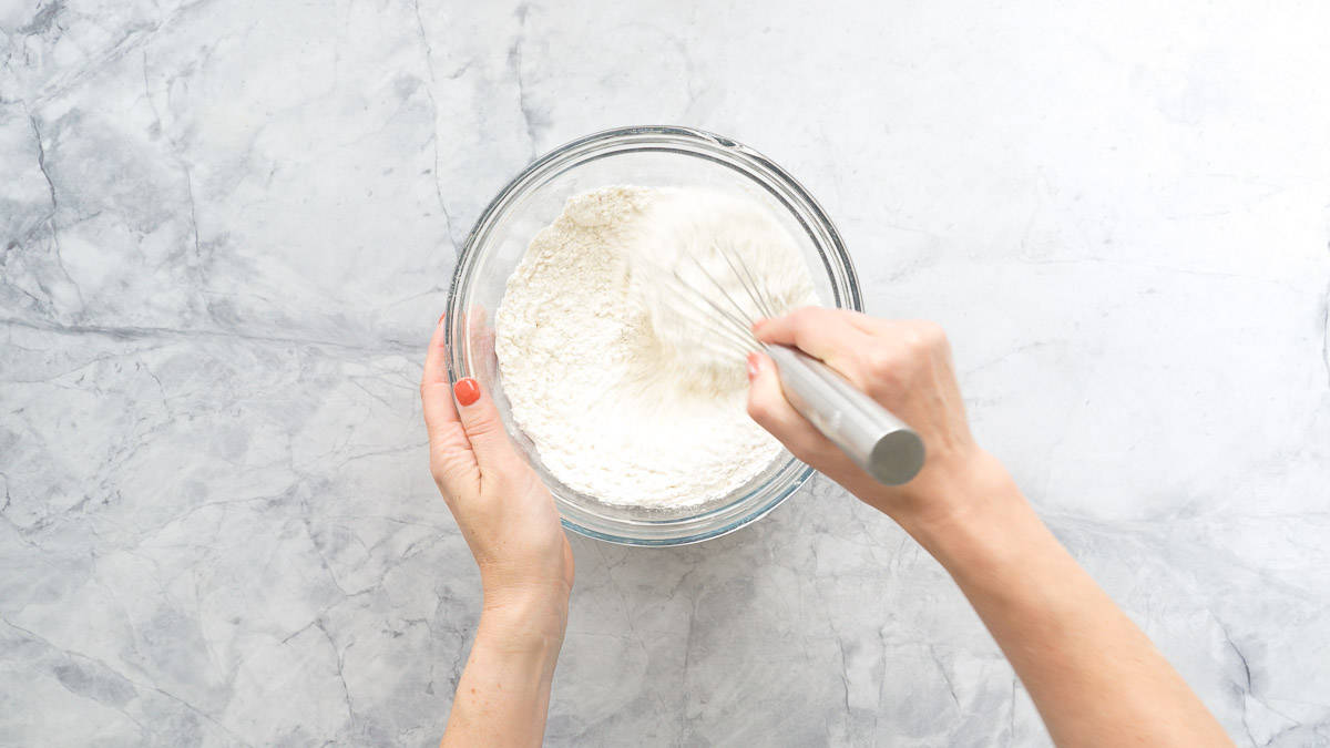 Dry ingredients being whisked together in a large glass bowl