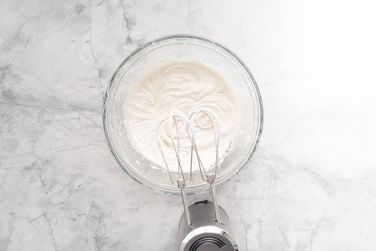 Coconut cream being whipped with an electric beater.