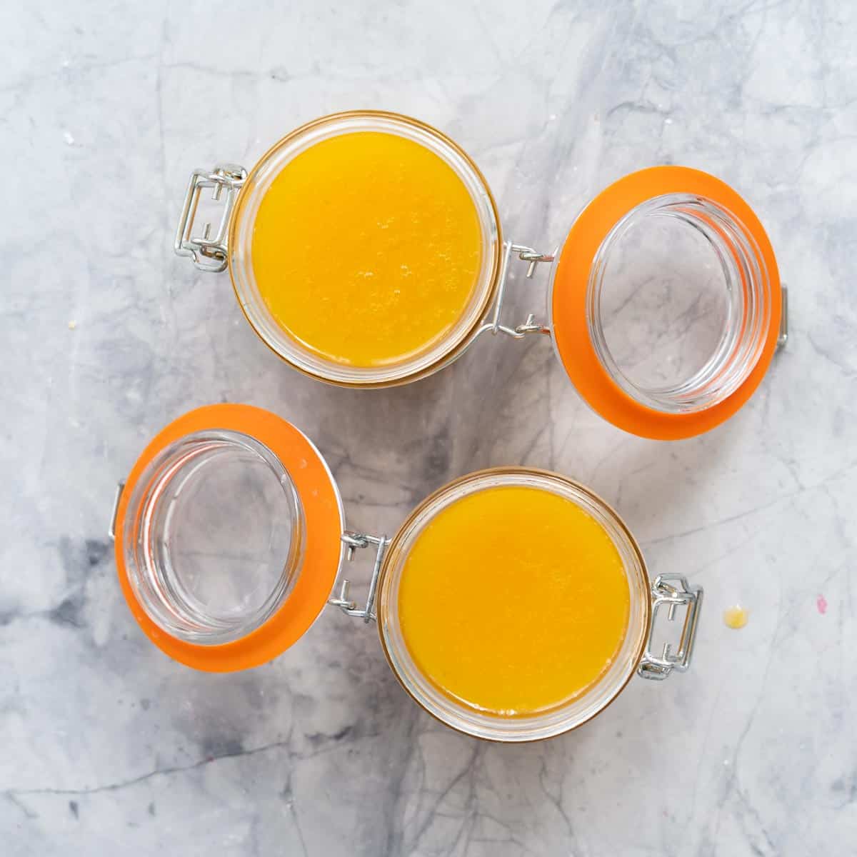 2 Glass maison jars full of thick Lemon Butter resting on the bench