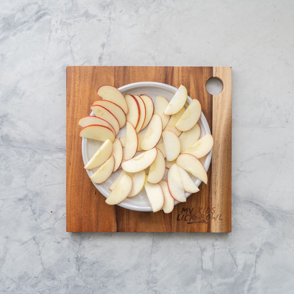 Apple slices arranged on a round white platter.