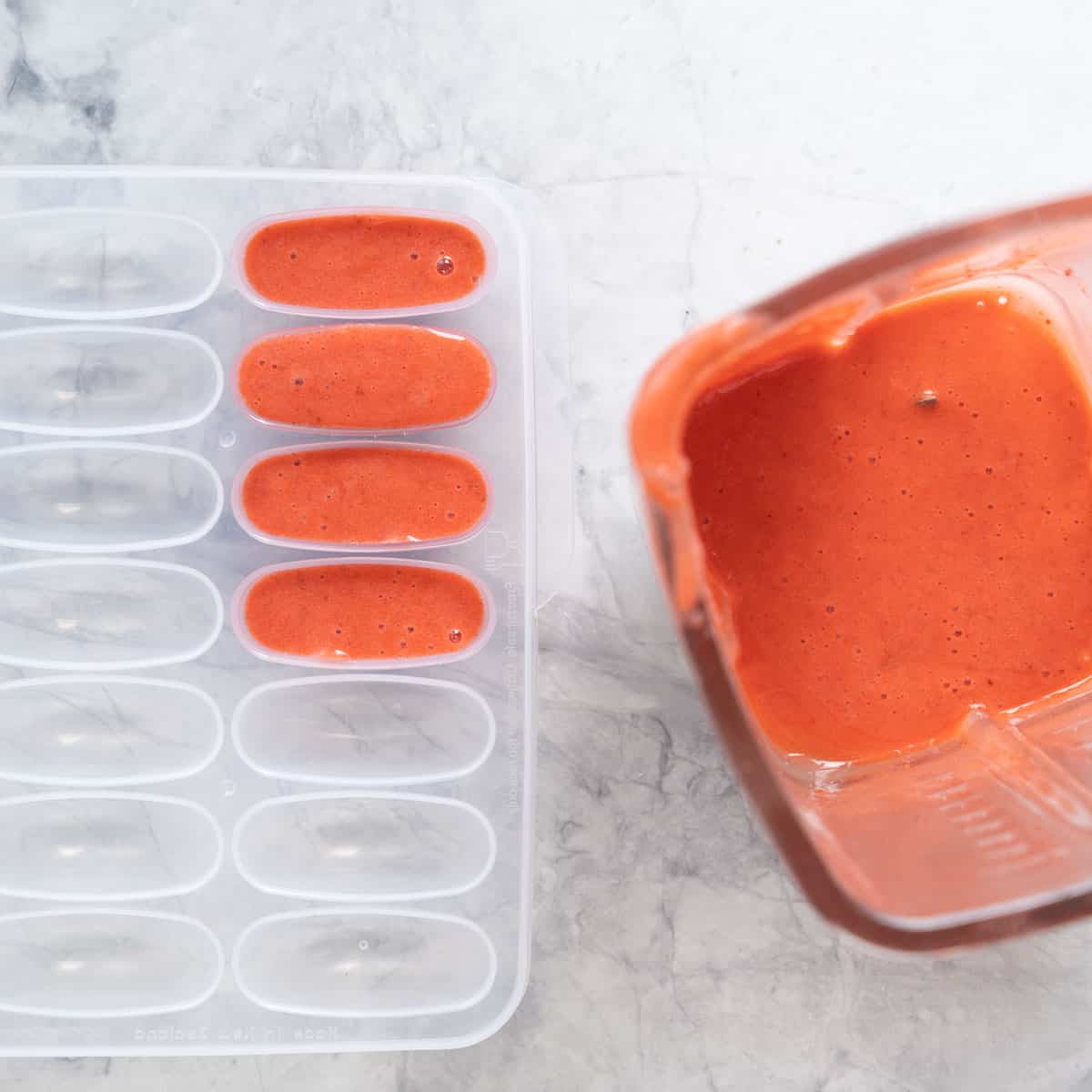 Red fruit puree in ice cube tray ready to be frozen.