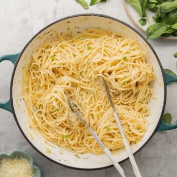 A ceramic dutch oven filled with butter coated spaghetti