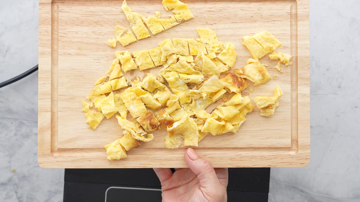 Omelette cut into bite sized pieces on a chopping board.