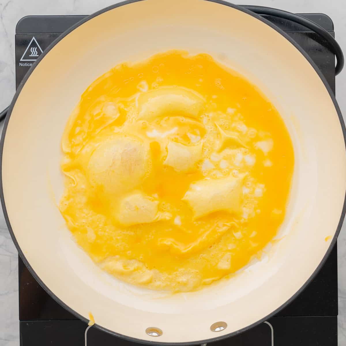 Omelette cooking in a ceramic wok.