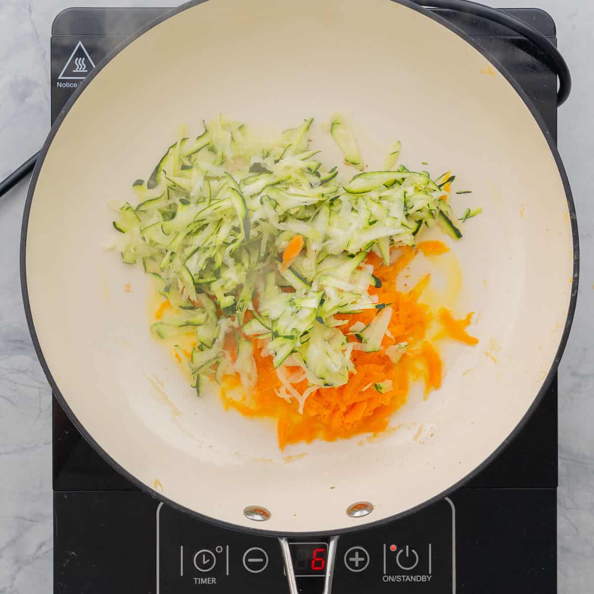 grated zucchini and carrot in a ceramic wok.