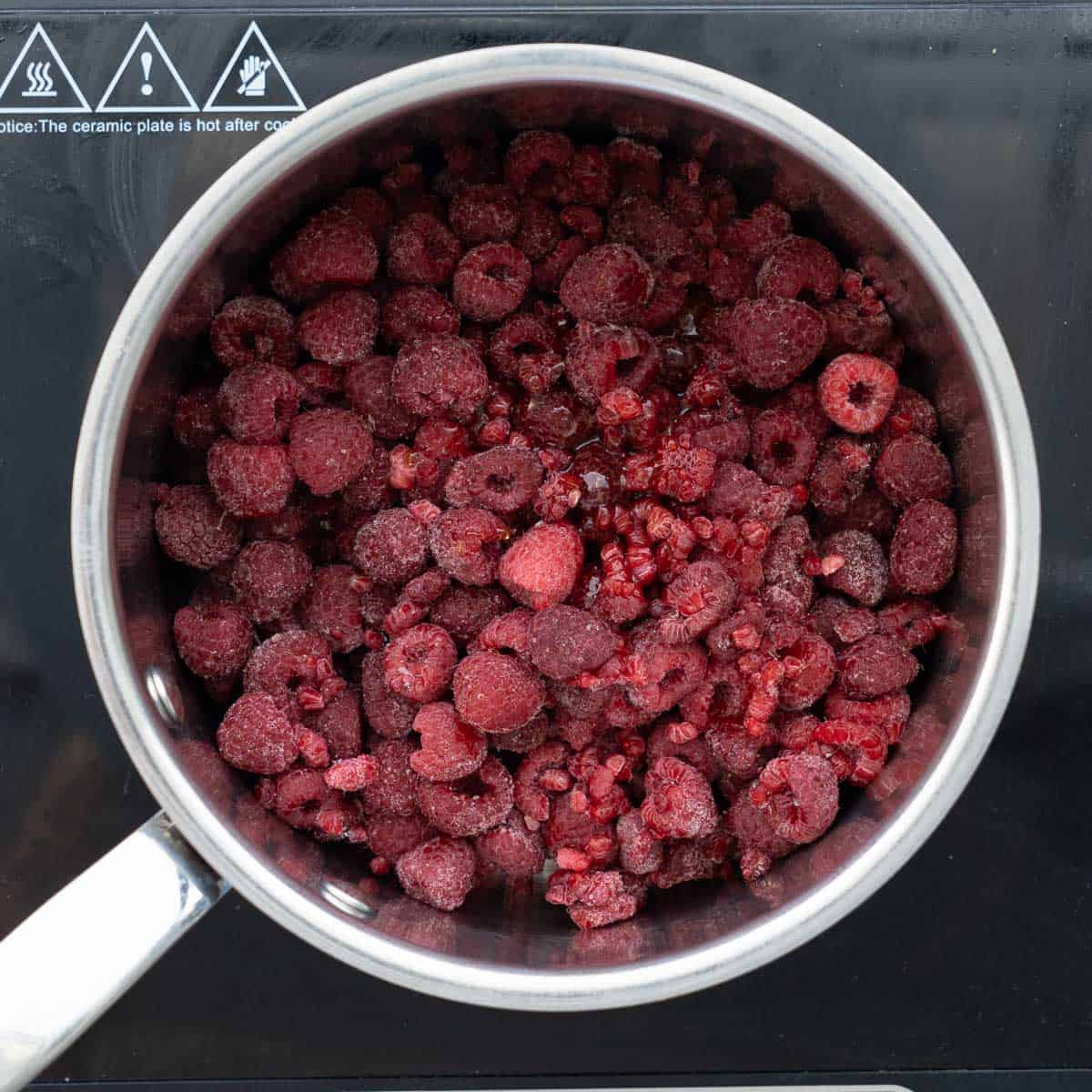 All the ingredients to make the raspberry puree in a saucepan on the element