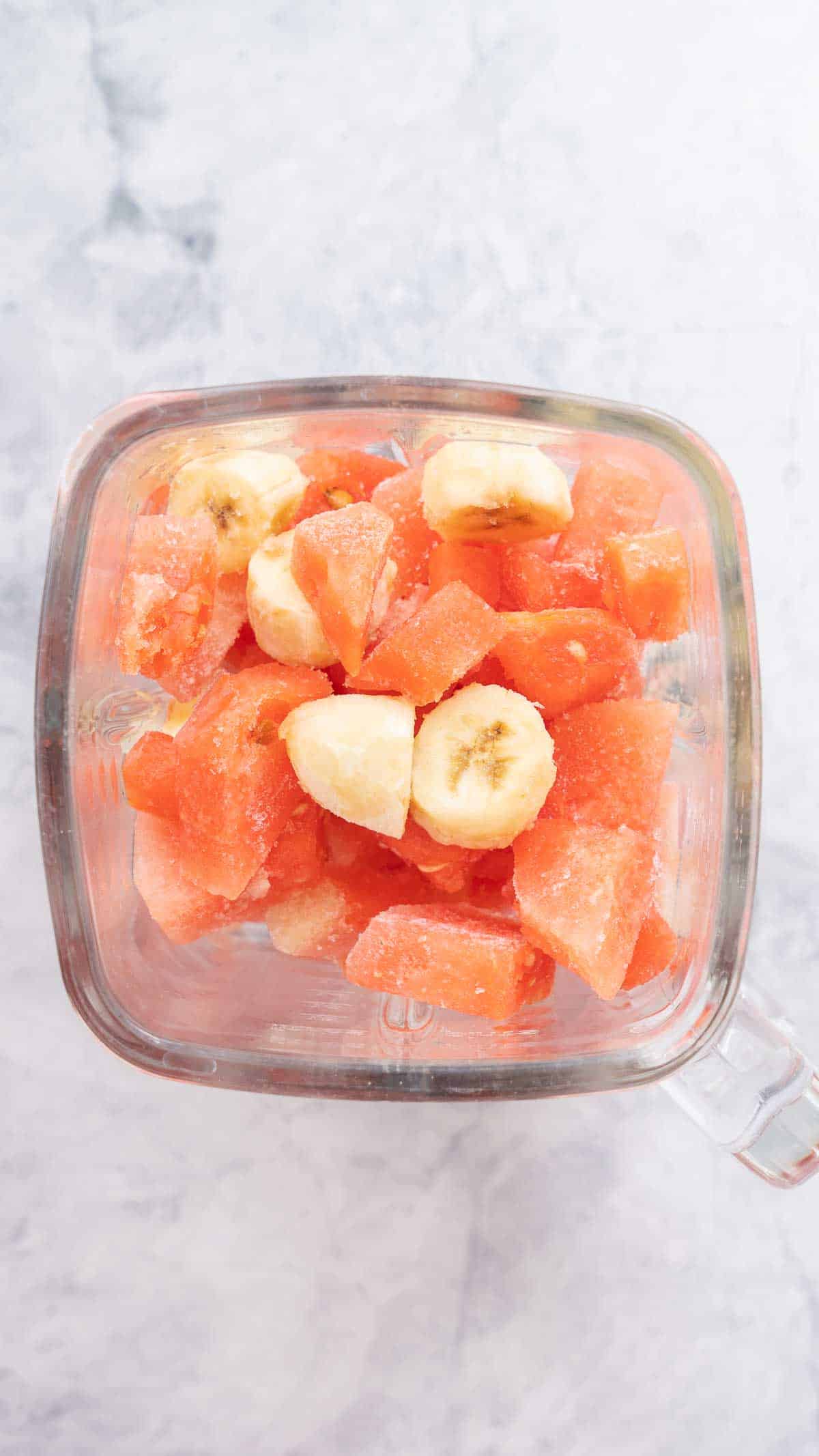 cubes of frozen watermelon and banana in the jug of a blender.