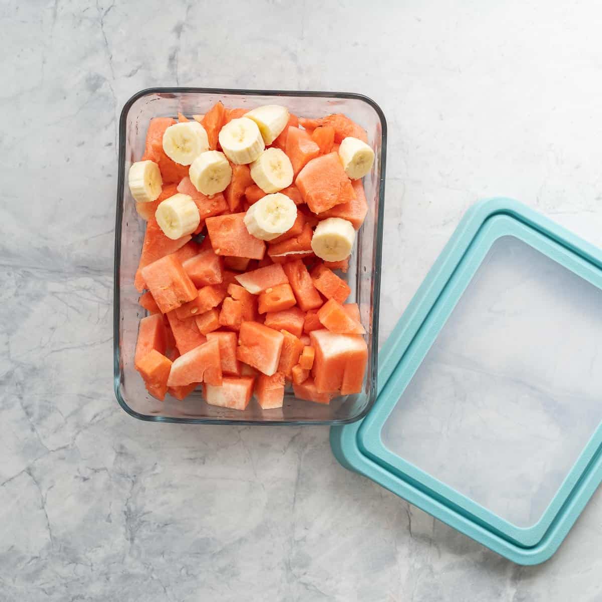 A large glass container of cubed watermelon and banana slices.