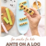 A hand holding a piece of celery filled with peanut butter topped with 4 raisins, with text overlay: Fun snacks for kids.