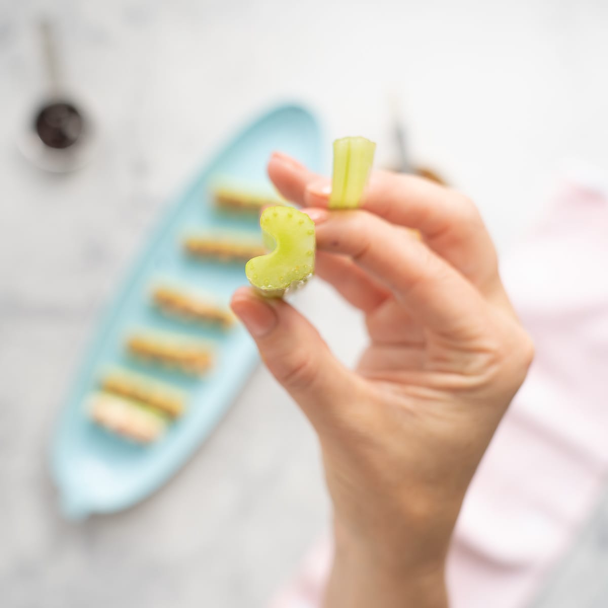 A hand holding a celery stick up which shows a slice off the bottom of it.