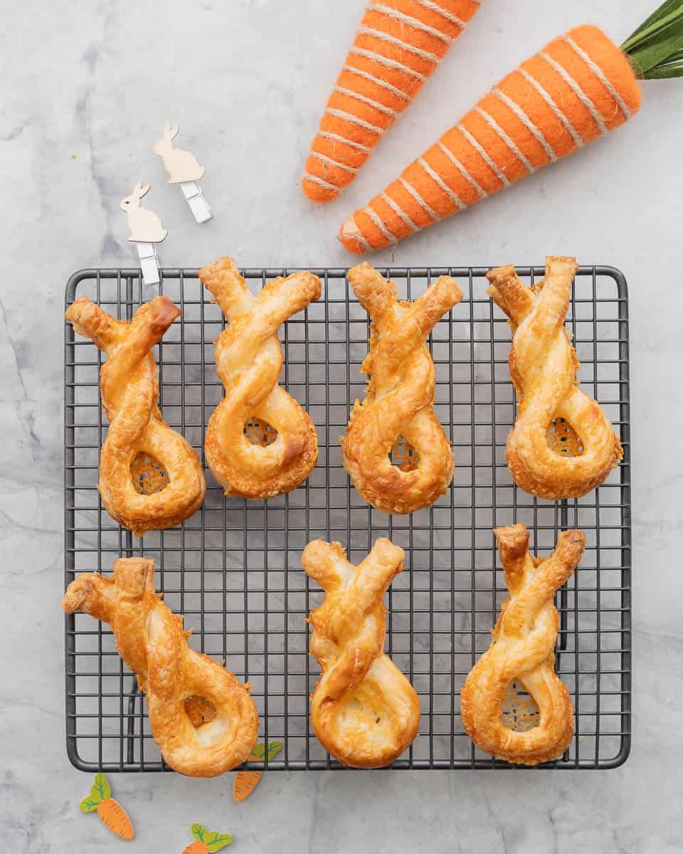 Seven these straw bunny twists on a cooling rack next to two large decorative felt carrots.