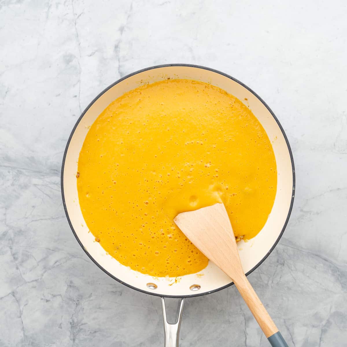 Lentil, carrot, coconut milk and mango sauce added to the pan which is resting on the bench.