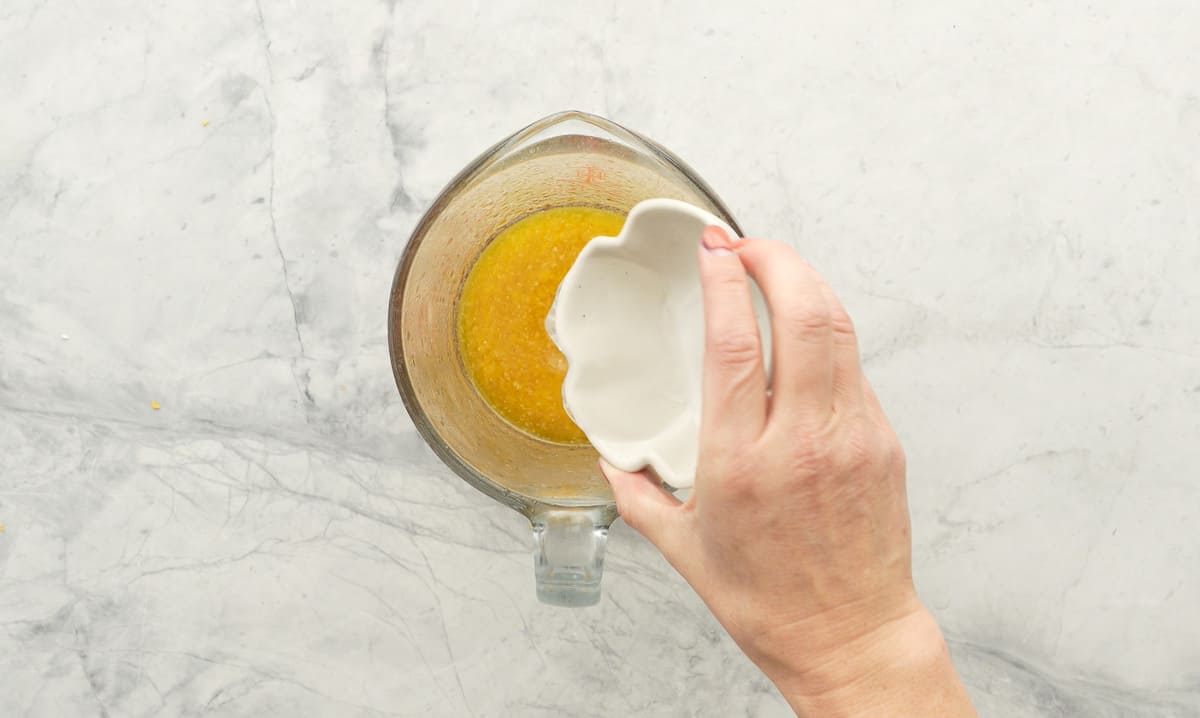 Clear liquid being poured into a glass measuring jug of melted butter.