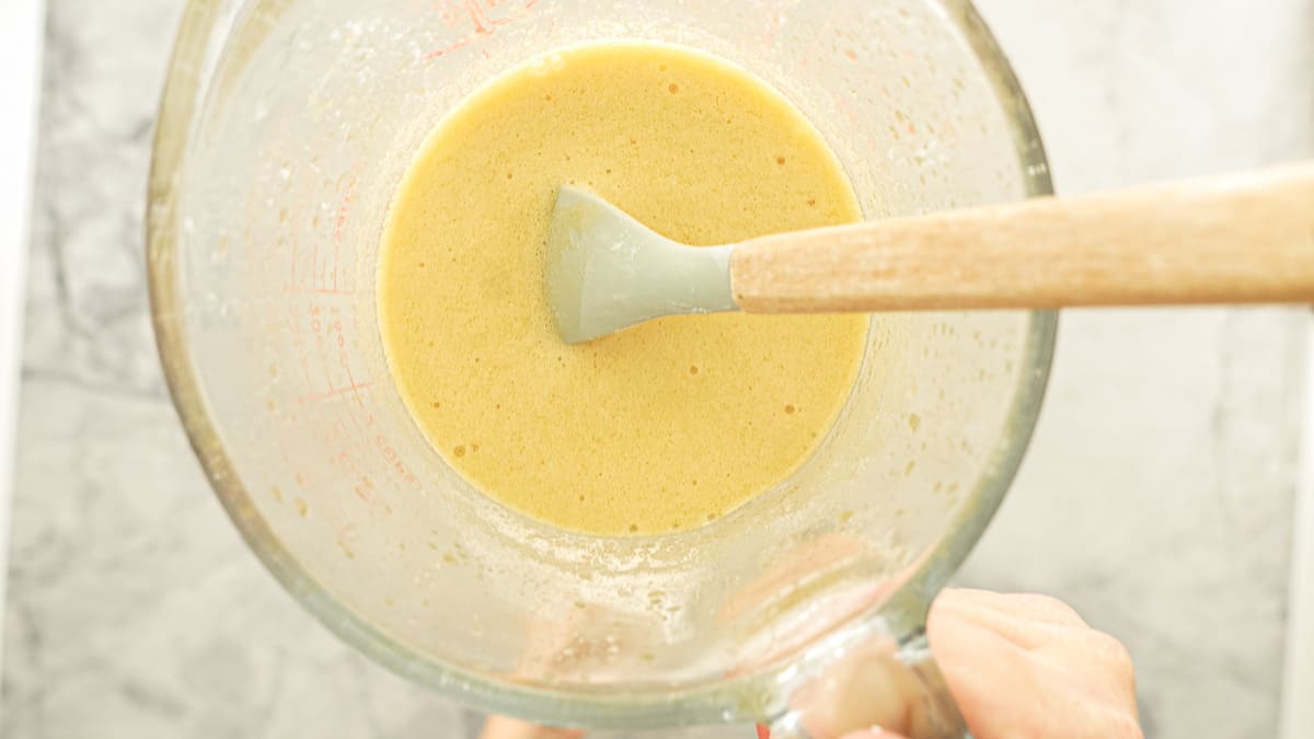 A jug of a light yellow coloured foam being held up to the camera.