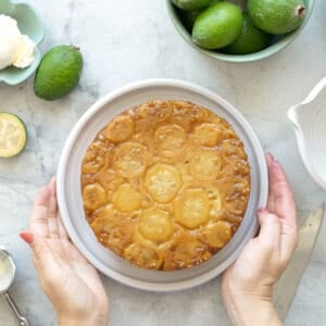 A round cake topped with a golssy layer of feijoa slices and caramel.