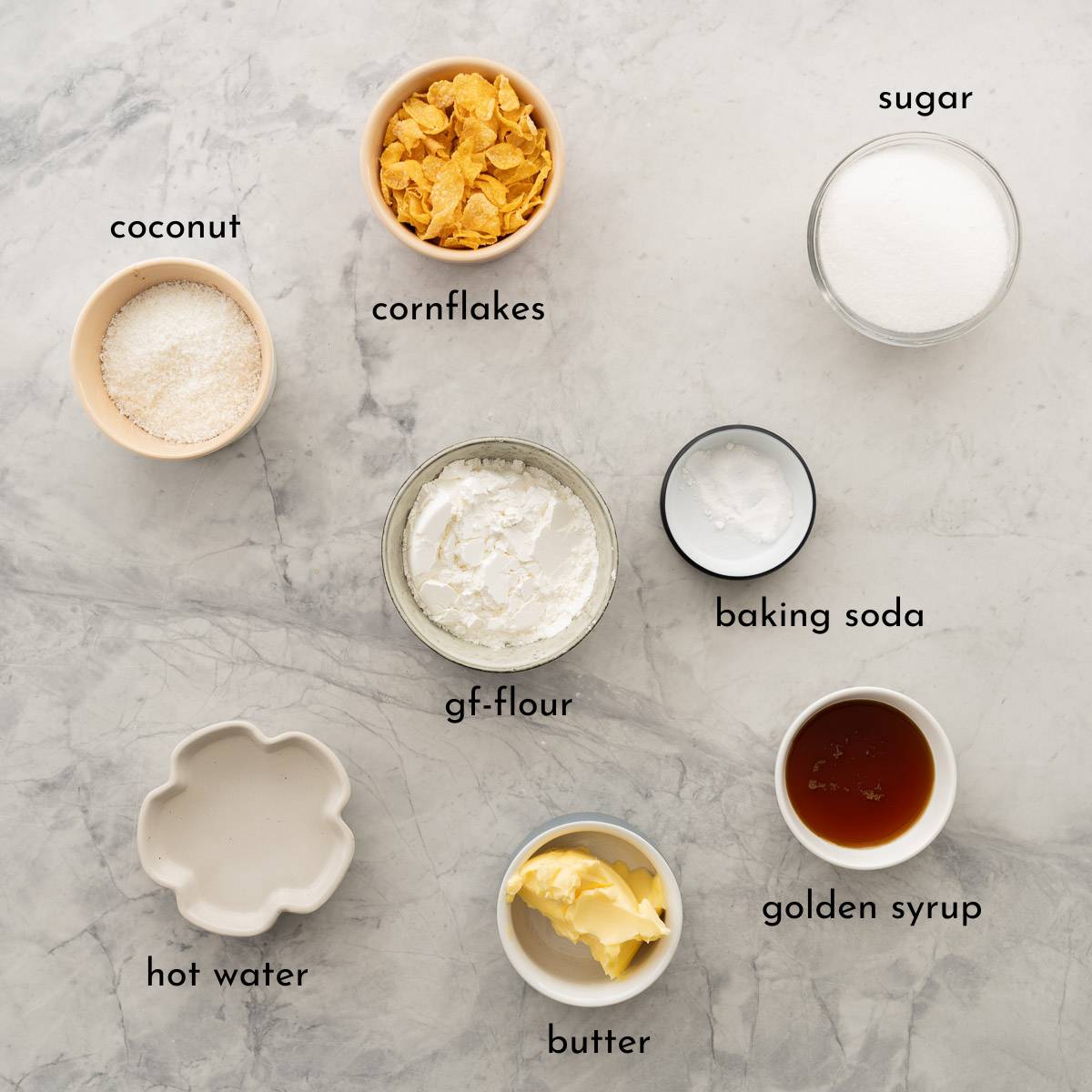 The ingredients to make gluten free Anzac biscuits laid out on a bench top with a name label.