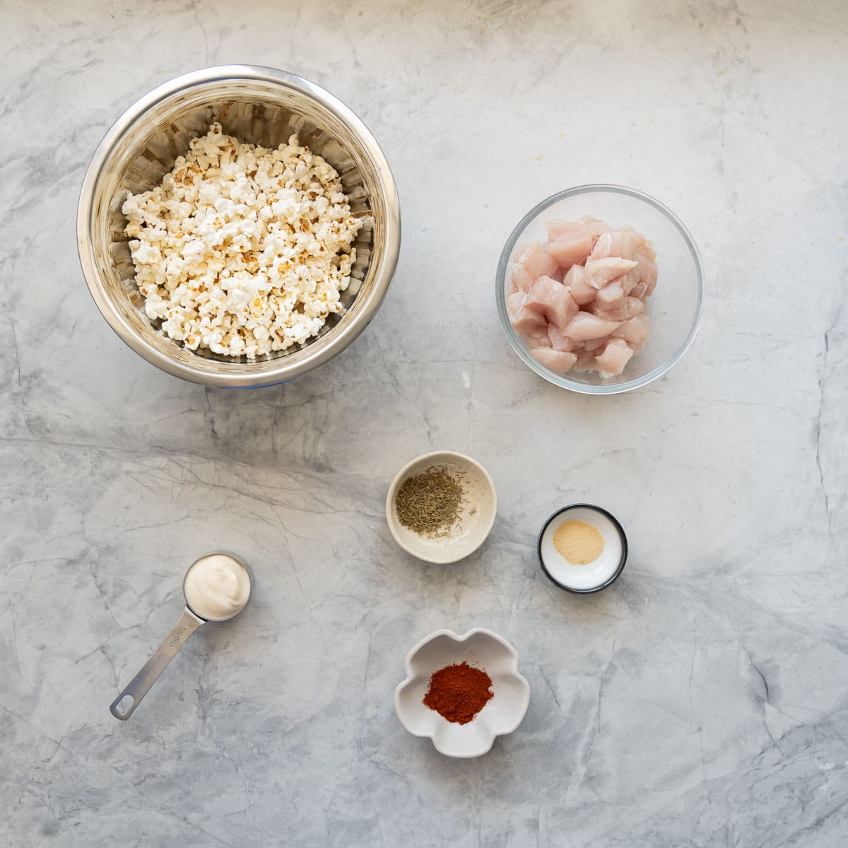 The ingredients to make popcorn chicken laid out on a bench top.