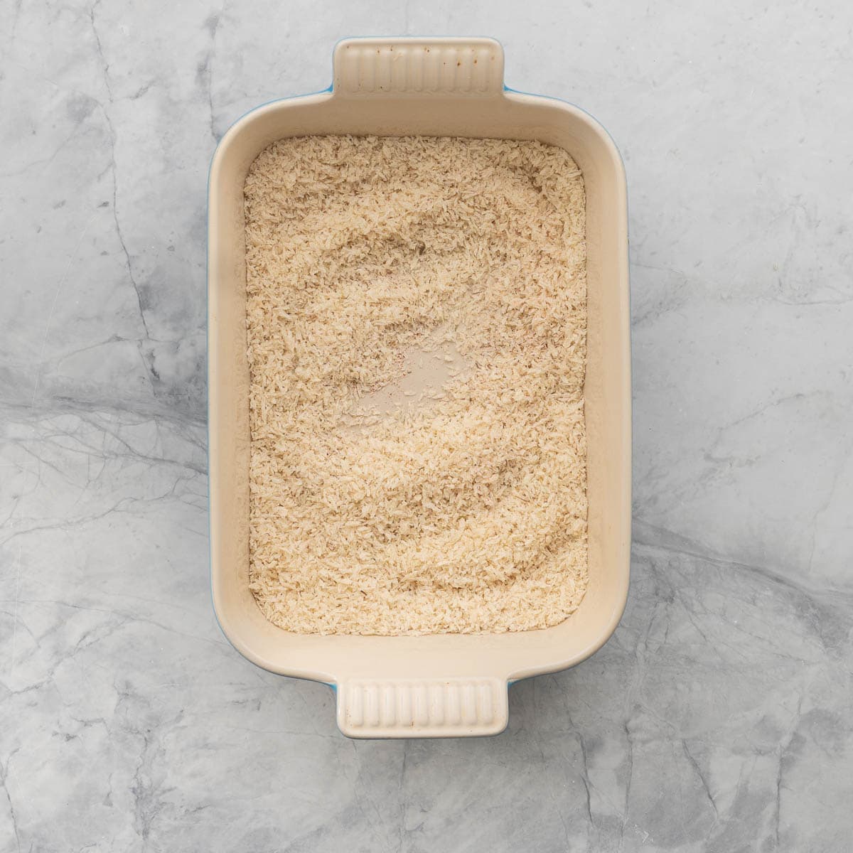 A rectangular baking dish of seasoned bread crumbs.