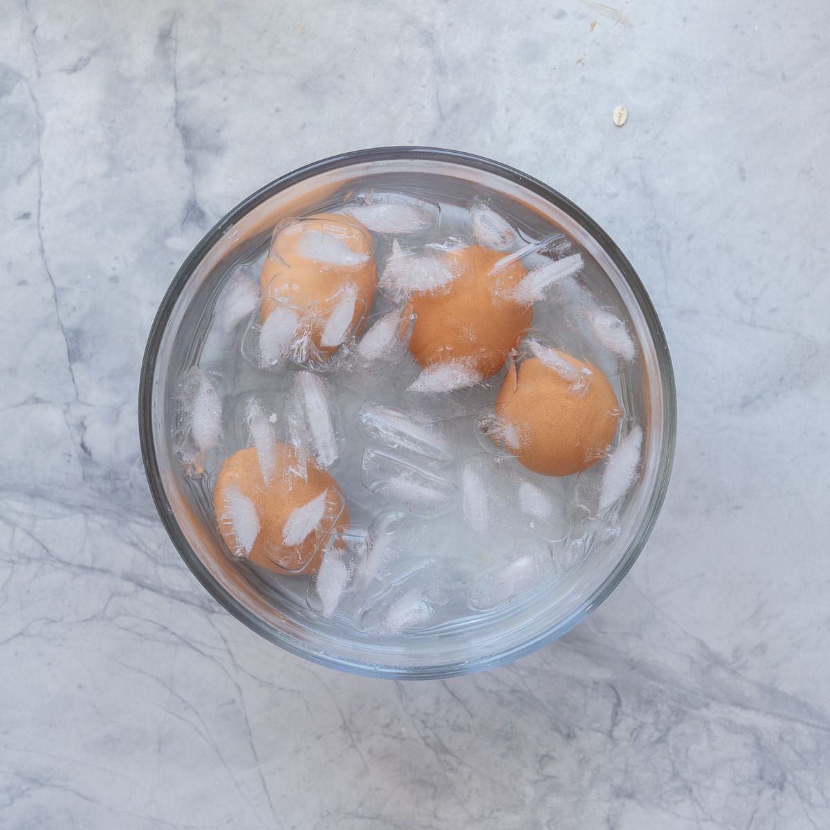 Four brown shelled eggs in a bowl of iced water.