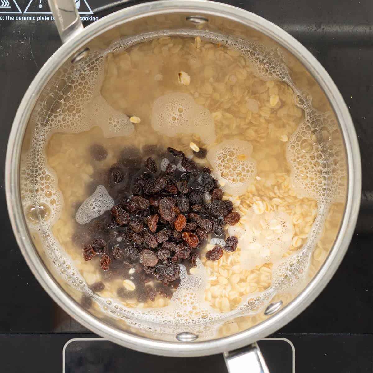 A saucepan of rolled oats, water and raisins.