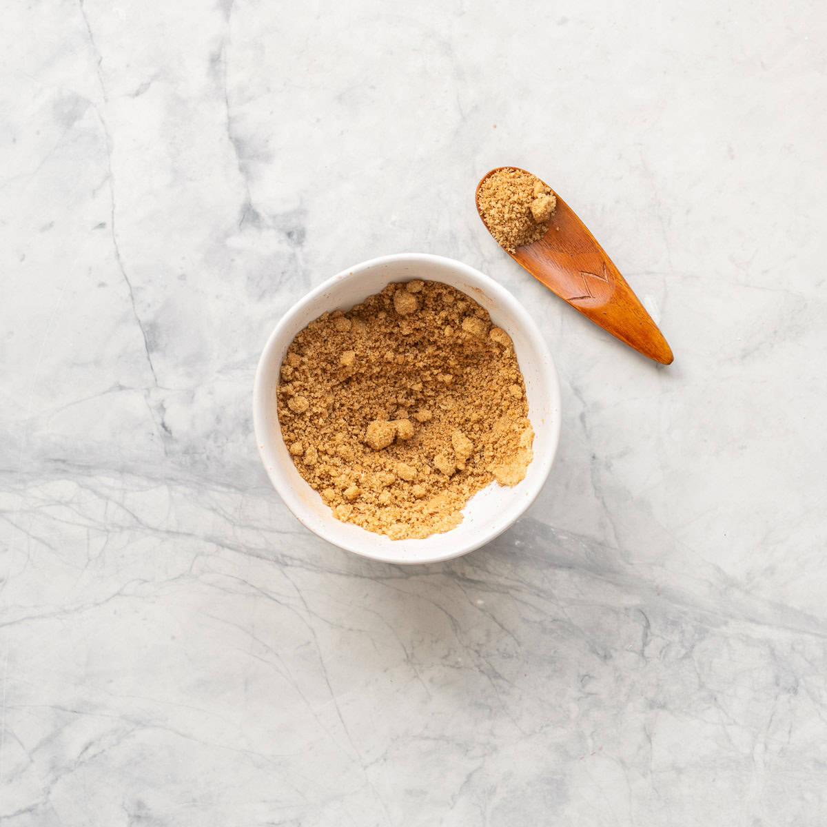 A small ceramic bowl of brown sugar cinnamon topping with a small wooden spoon.