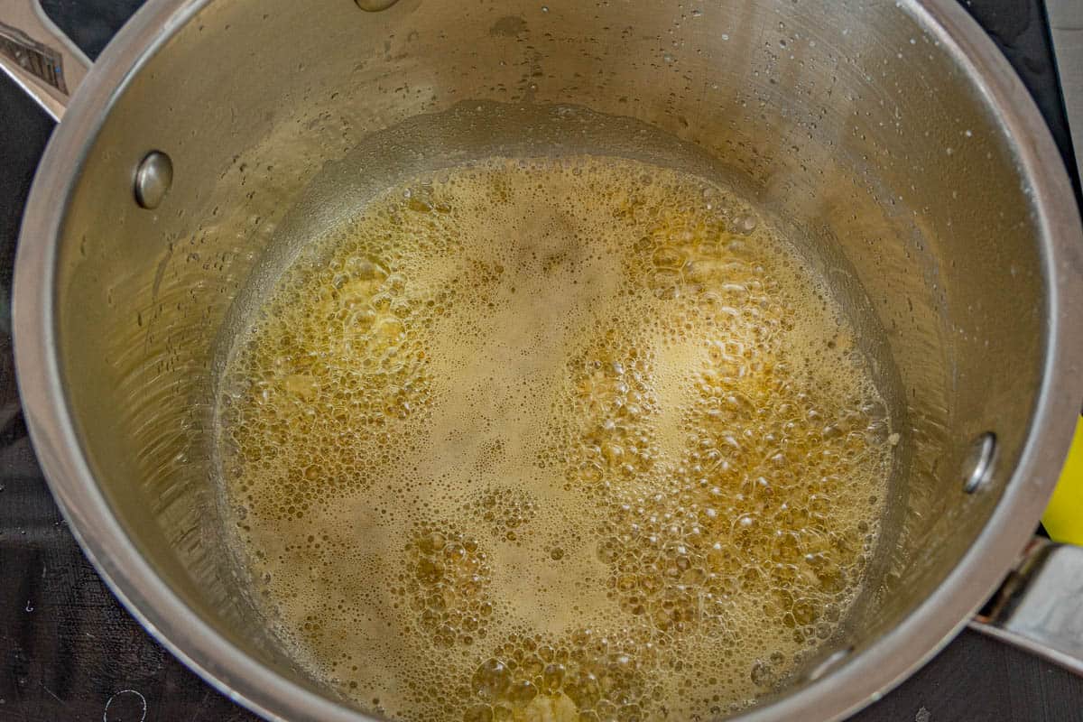 Garlic sizzling in melted butter in the bottom of a saucepan.