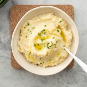 A bowl of potato and cauliflower mash, drizzled with olive oil and sprinkled with chopped chives.
