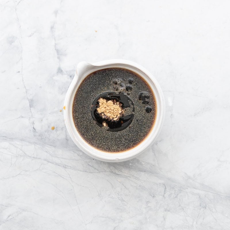 Small bowl on benchtop with sauce for teriyaki baked salmon.