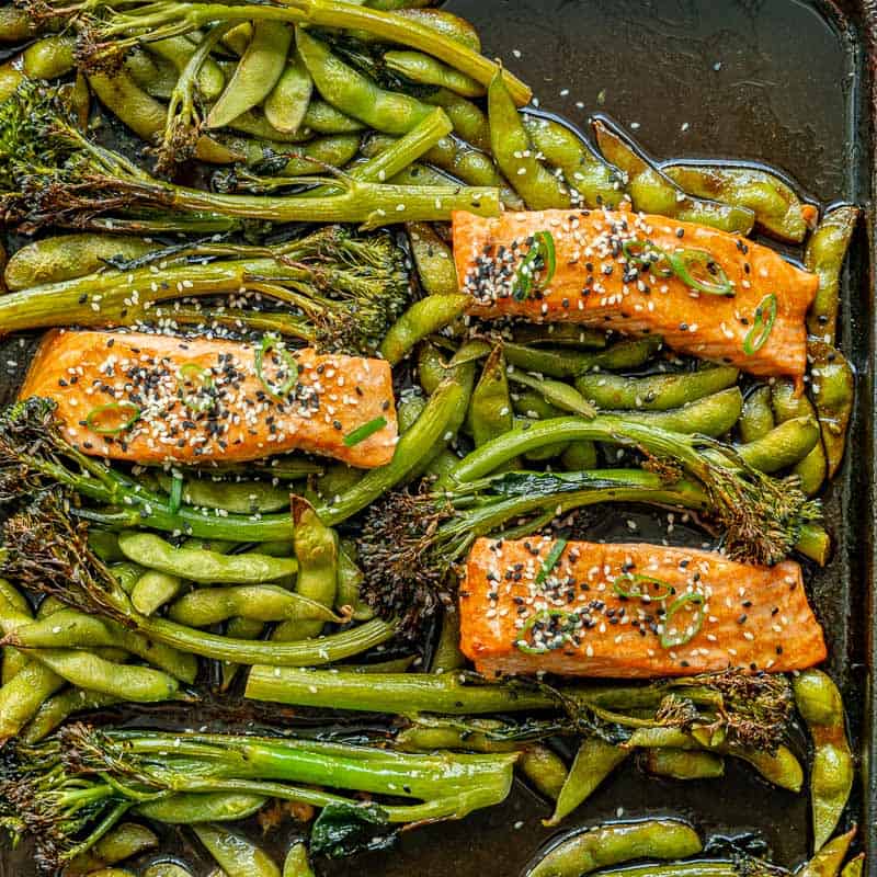 Cooked teriyaki salmon and green vegetables on baking tray.