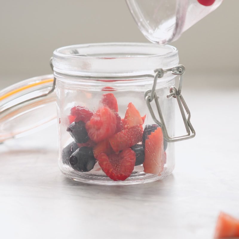 Mixed berries in the bottom of a small mason jar.