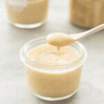 A small glass jar of peach pudding with a spoonful being scooped out of it.