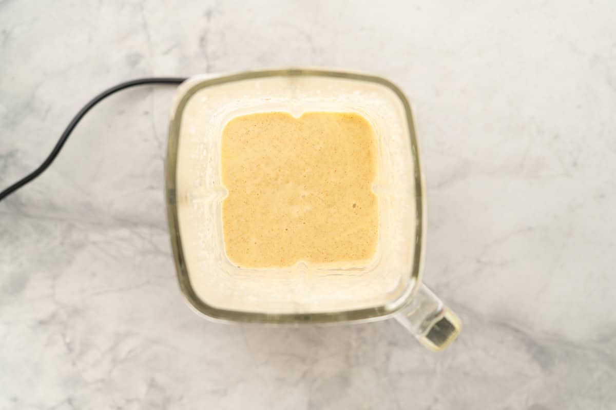 Looking down into the jug of a blender of smooth creamy peach blended chia pudding.