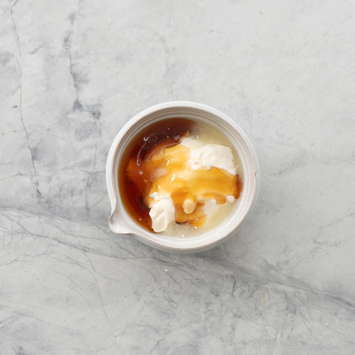 A small bowl with spout filled with honey yoghurt and mayonnaise.