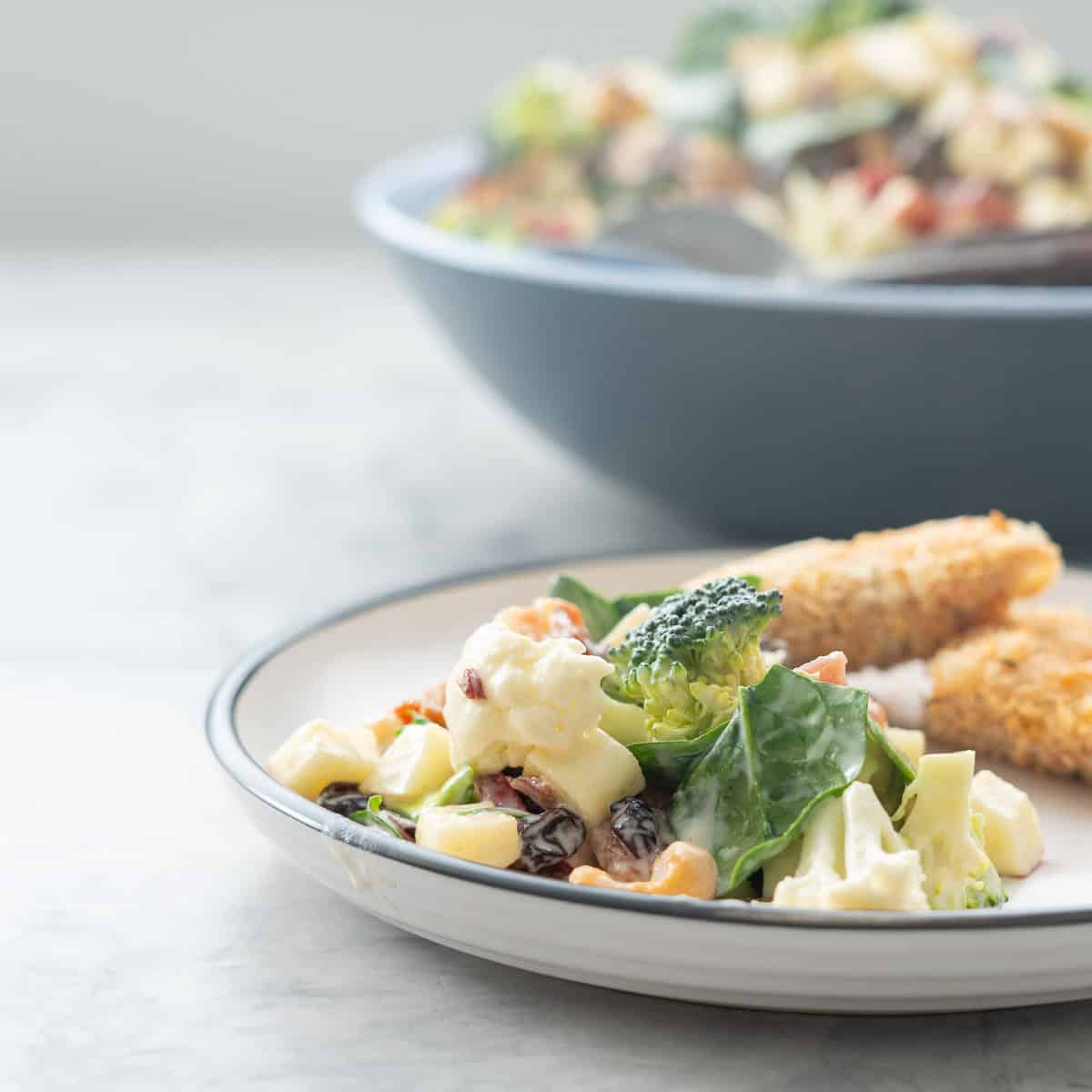 A salad with broccoli cauliflower and spinach on a white plate.