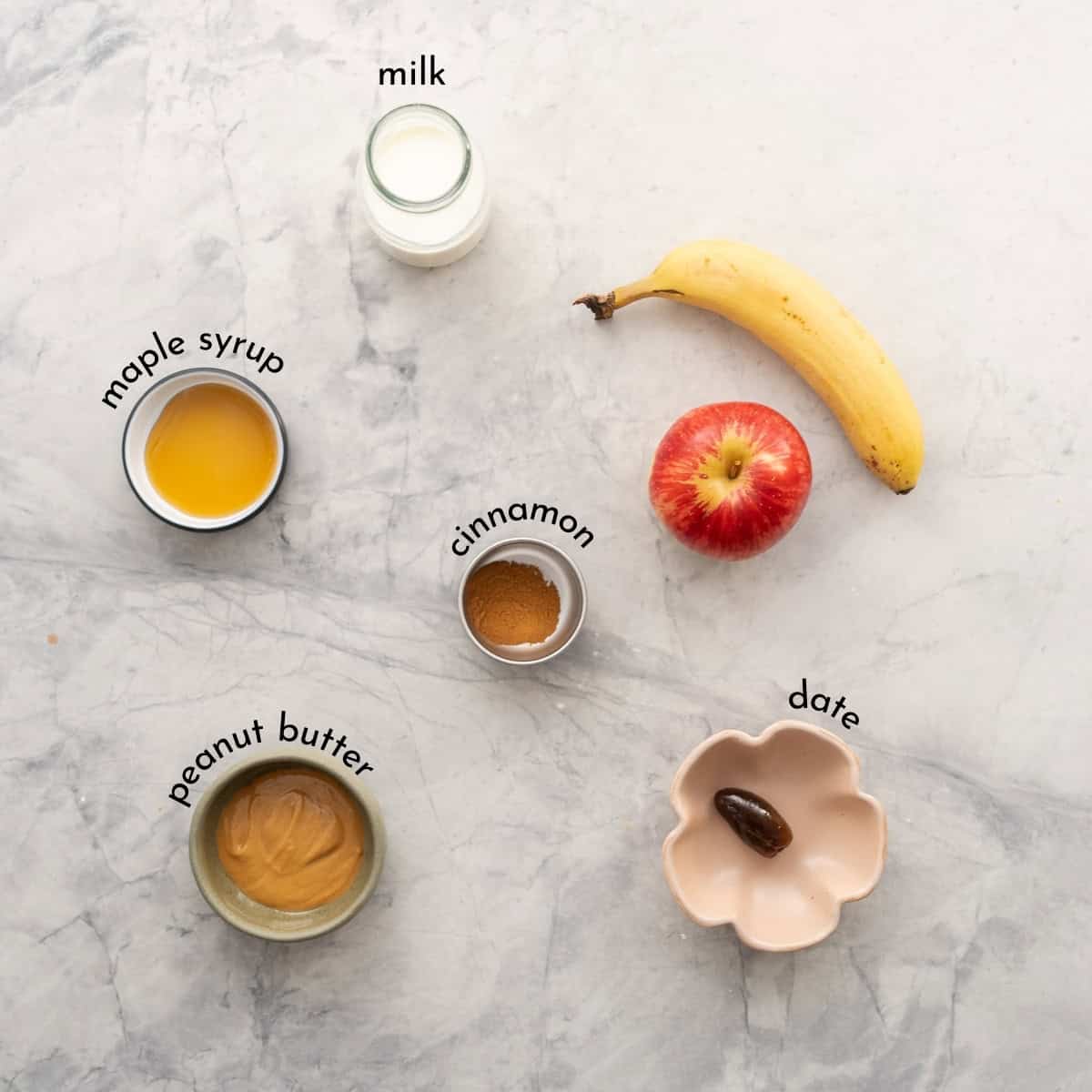 The ingredients to make apple smoothie laid out on a bench top with text overlay labels.